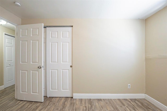 unfurnished bedroom featuring a closet, baseboards, and light wood-style floors