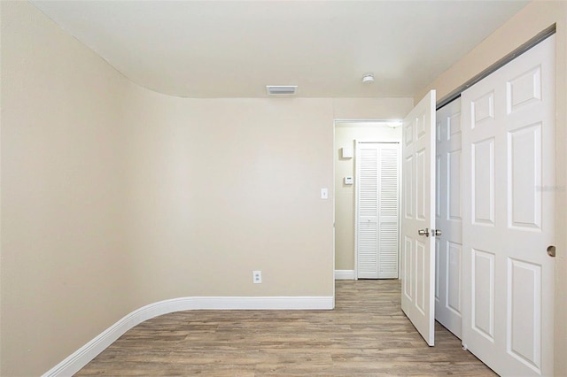 unfurnished bedroom with visible vents, light wood-style floors, baseboards, and a closet