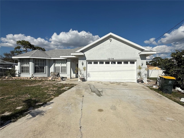 ranch-style house with a garage, driveway, a shingled roof, and stucco siding