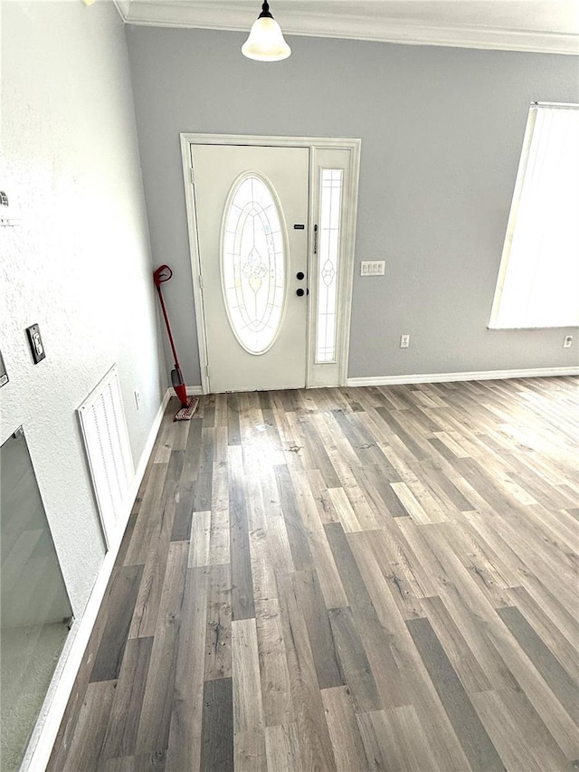 foyer entrance with ornamental molding, wood finished floors, visible vents, and baseboards