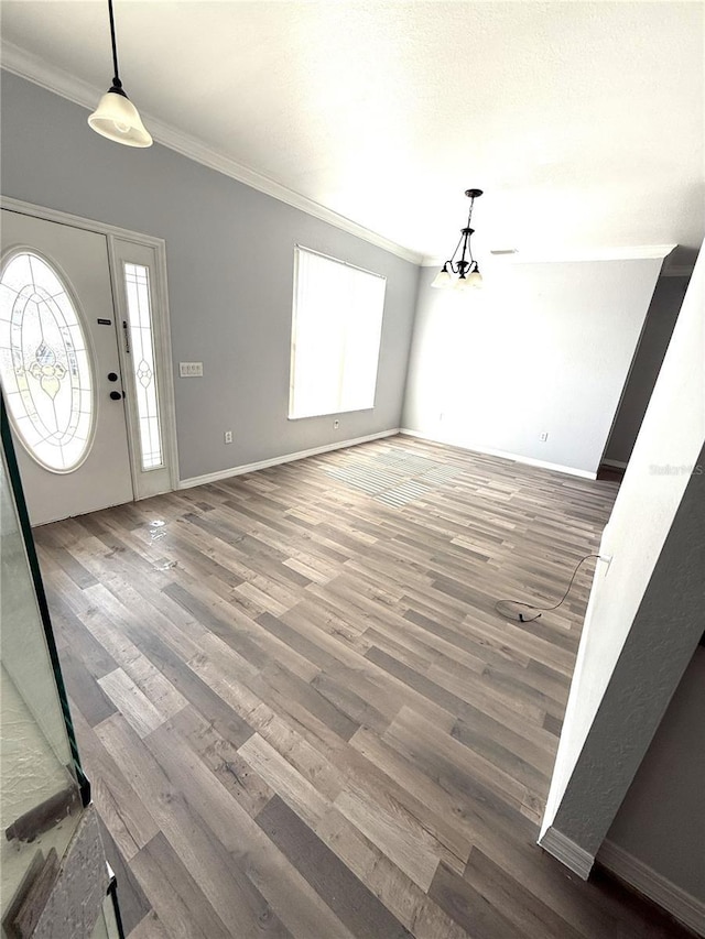 foyer with ornamental molding, baseboards, and wood finished floors