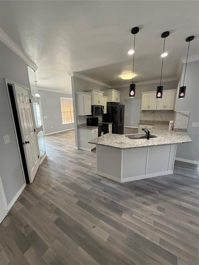 3206 Valerie Blvd, Sebring, FL 33870 - kitchen featuring a peninsula, wood finished floors, a sink, white cabinetry, and black appliances