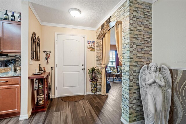 entryway featuring a textured ceiling, arched walkways, baseboards, dark wood finished floors, and crown molding