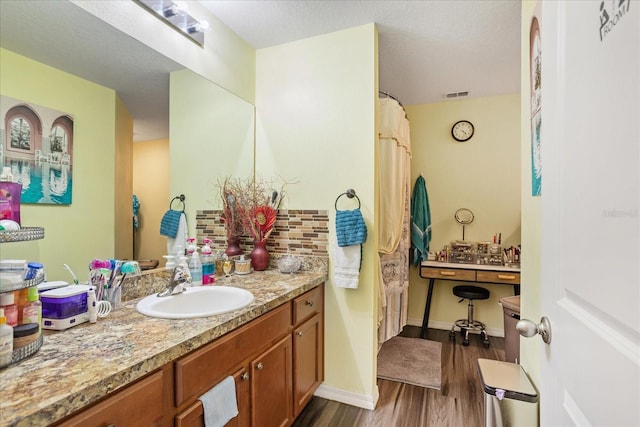 bathroom with visible vents, vanity, baseboards, and wood finished floors