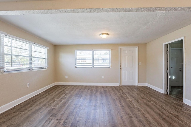 unfurnished room with a wealth of natural light, baseboards, dark wood-type flooring, and a textured ceiling