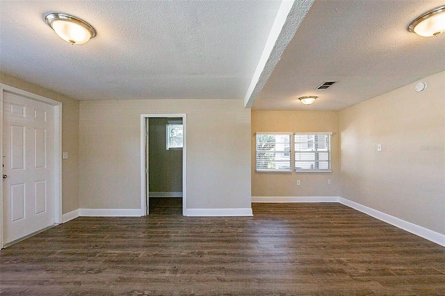 spare room with dark wood finished floors, baseboards, and visible vents