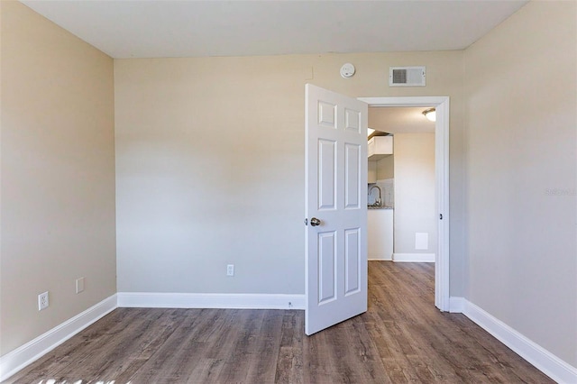 unfurnished room featuring visible vents, baseboards, and wood finished floors