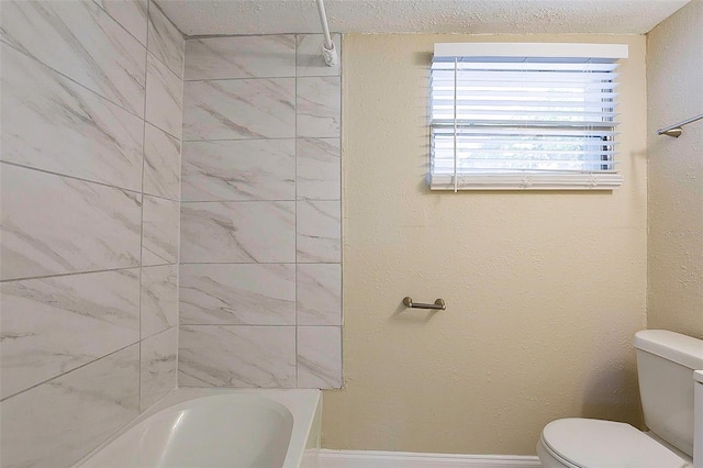 full bath featuring washtub / shower combination, toilet, and a textured wall