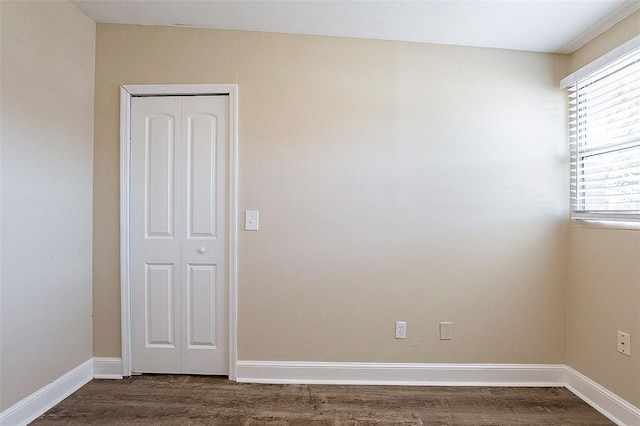 unfurnished room with baseboards and dark wood-style flooring