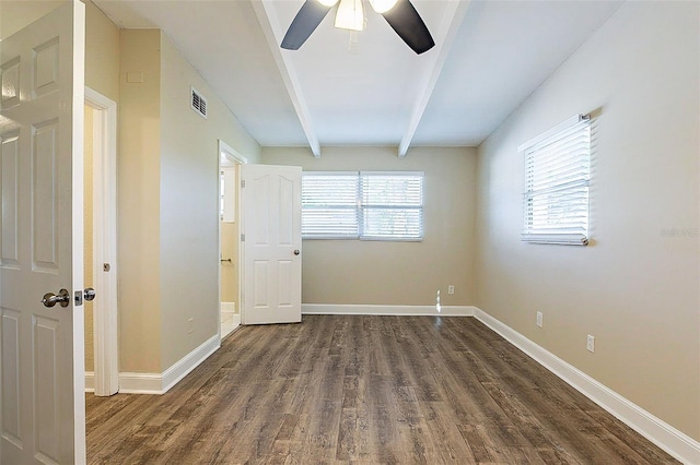 spare room with dark wood-type flooring, beamed ceiling, baseboards, and visible vents