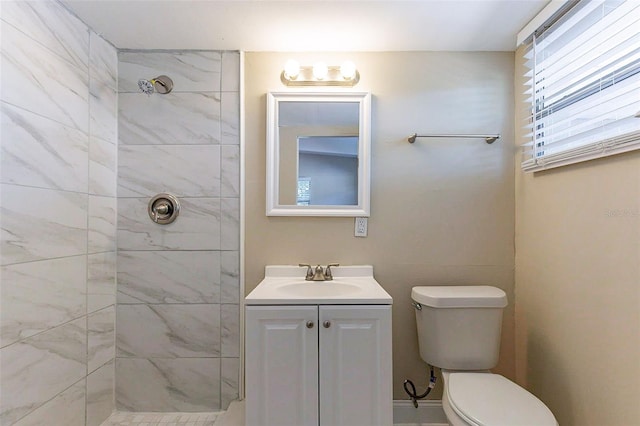 bathroom with toilet, tiled shower, and vanity