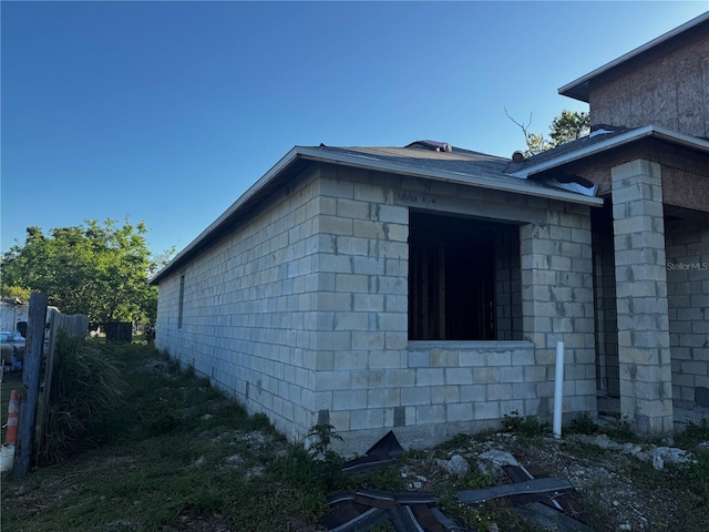 view of side of home with concrete block siding and fence