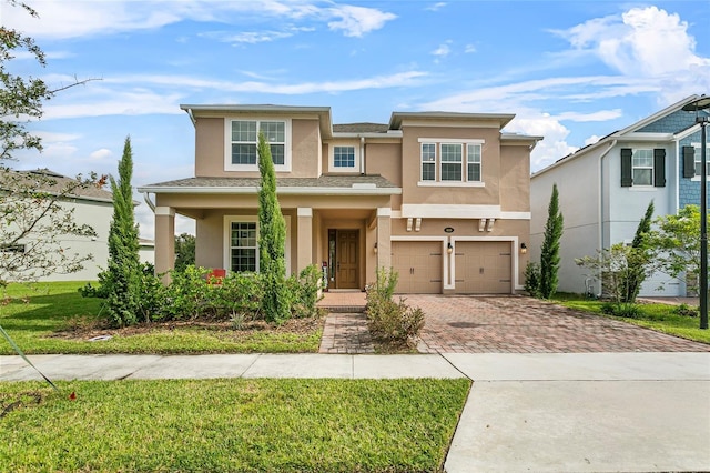 view of front of home featuring decorative driveway, an attached garage, and stucco siding