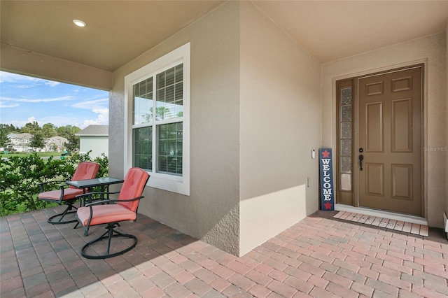 entrance to property featuring a porch and stucco siding