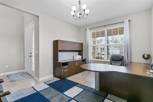 home office with baseboards, light wood finished floors, and a notable chandelier