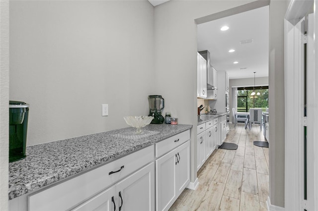 kitchen featuring visible vents, light stone counters, light wood-style floors, white cabinetry, and recessed lighting