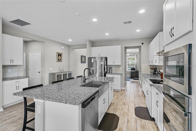 kitchen featuring stainless steel appliances, visible vents, a sink, and light wood-style flooring