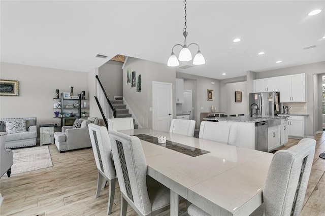 dining room featuring visible vents, light wood-style flooring, stairway, an inviting chandelier, and recessed lighting