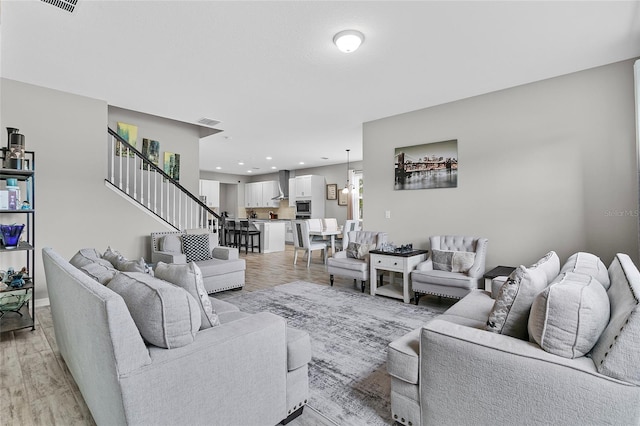 living area featuring light wood-style floors, recessed lighting, visible vents, and stairs