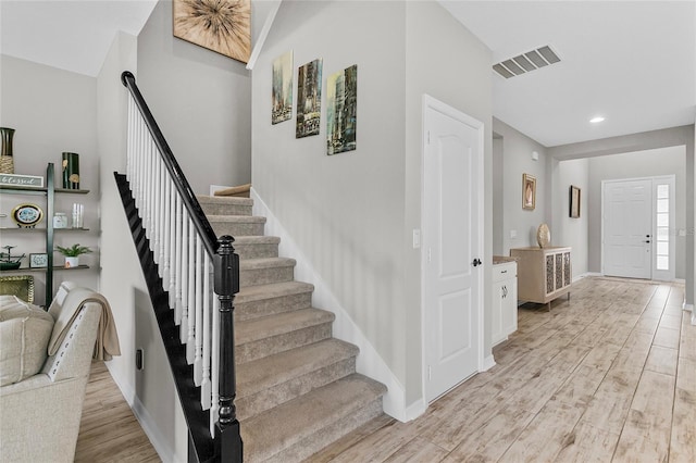 stairway with baseboards, visible vents, wood finished floors, and recessed lighting