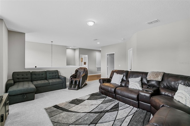 carpeted living room featuring visible vents and a textured ceiling