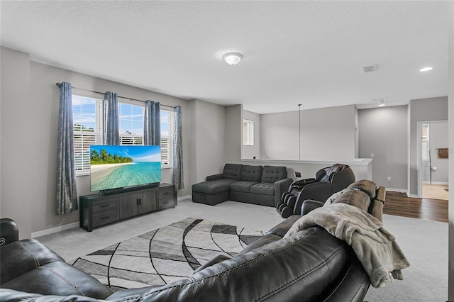 living room with light colored carpet, visible vents, baseboards, and a textured ceiling