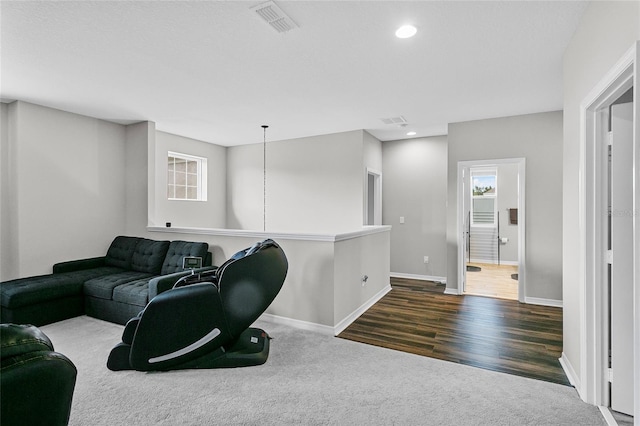 carpeted living area featuring recessed lighting, visible vents, baseboards, and wood finished floors