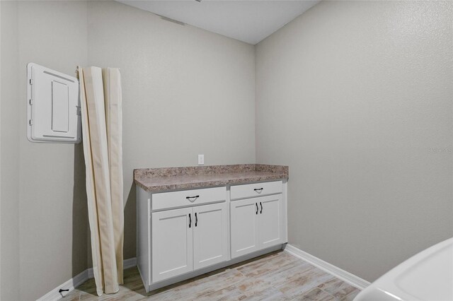 clothes washing area with light wood-style flooring and baseboards