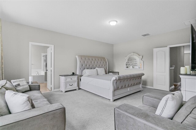 bedroom with baseboards, visible vents, light carpet, and ensuite bath