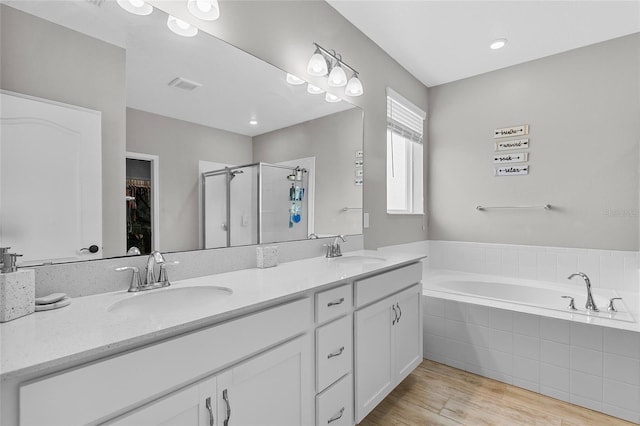 bathroom featuring visible vents, a sink, a shower stall, and wood finished floors