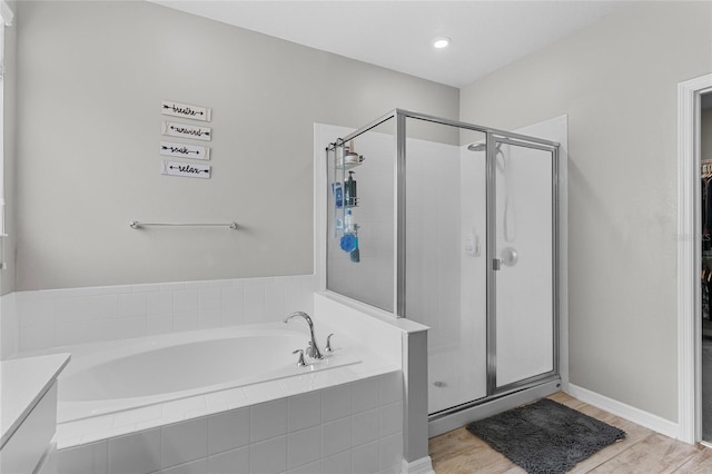 full bathroom featuring a stall shower, a garden tub, and wood finished floors