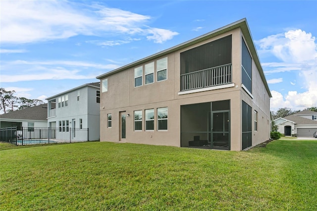 rear view of house featuring a sunroom, stucco siding, a yard, and fence