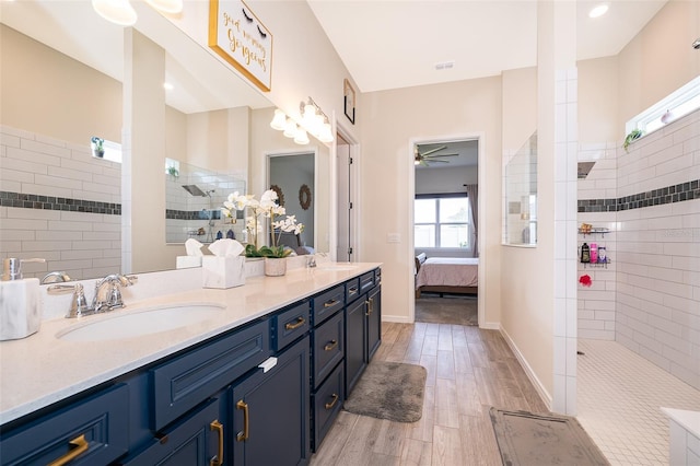 full bathroom featuring a walk in shower, double vanity, wood finished floors, and a sink