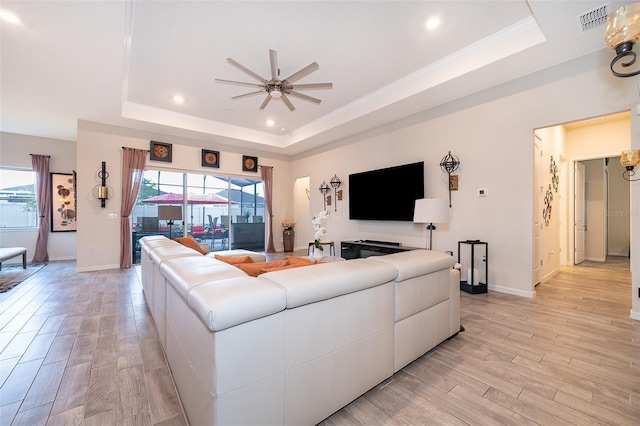 living area with light wood finished floors, a tray ceiling, and a wealth of natural light