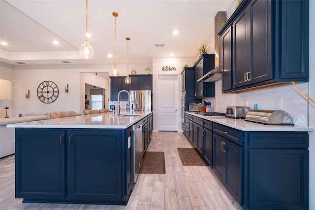 kitchen featuring stainless steel appliances, open floor plan, a sink, and blue cabinetry