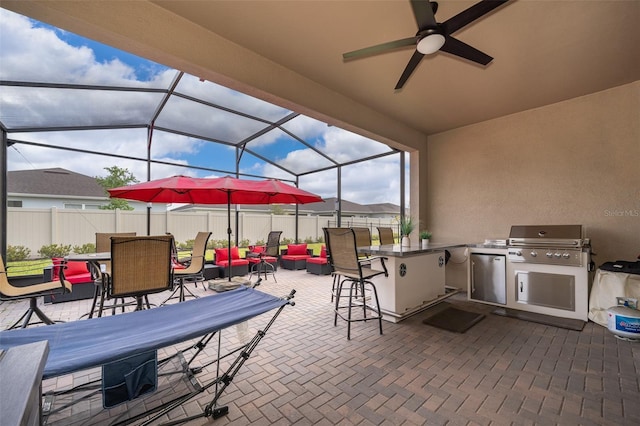 view of patio with an outdoor kitchen, area for grilling, glass enclosure, outdoor dry bar, and fence