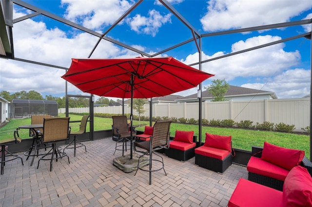 view of patio featuring glass enclosure, outdoor lounge area, and a fenced backyard