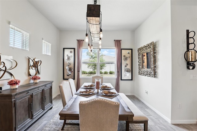 dining area with baseboards, a chandelier, and light wood-style flooring