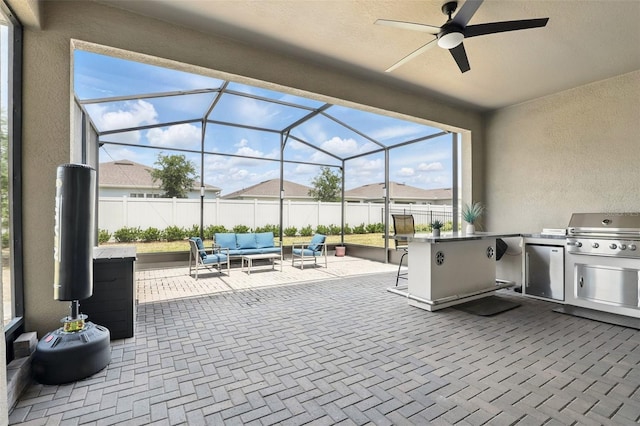 view of patio / terrace featuring an outdoor living space, glass enclosure, exterior kitchen, area for grilling, and ceiling fan