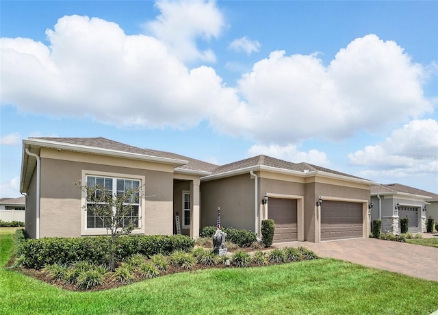 prairie-style house with stucco siding, an attached garage, decorative driveway, and a front yard