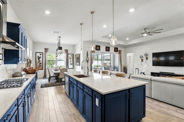 kitchen with blue cabinets, stainless steel appliances, a sink, open floor plan, and ceiling fan