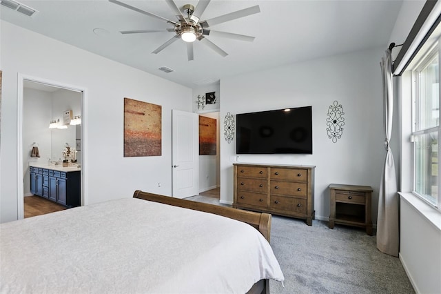 bedroom featuring baseboards, ensuite bath, visible vents, and a ceiling fan