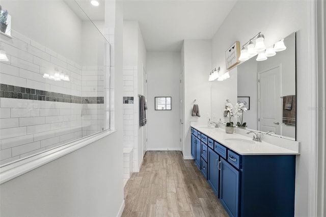 full bath featuring double vanity, wood finished floors, a sink, and a walk in shower