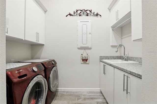 laundry area with electric panel, a sink, baseboards, independent washer and dryer, and cabinet space