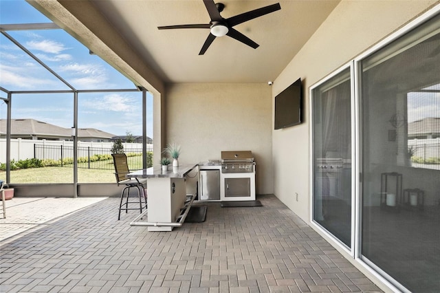 view of patio featuring glass enclosure, fence, exterior bar, a ceiling fan, and area for grilling