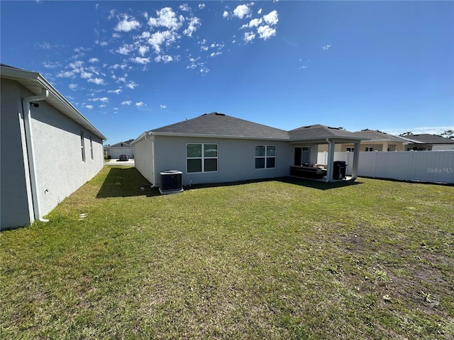 back of property with a yard, central AC unit, fence, and stucco siding