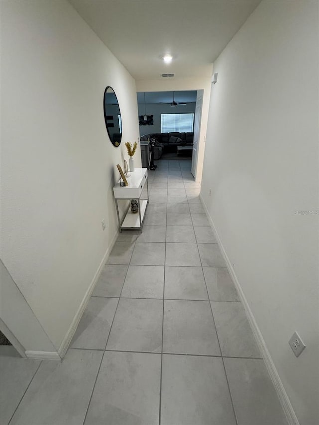 hall featuring visible vents, baseboards, and light tile patterned flooring