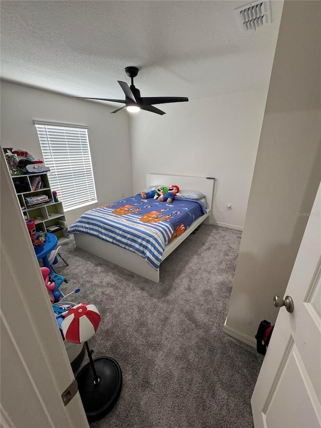 carpeted bedroom featuring a textured ceiling, ceiling fan, and visible vents