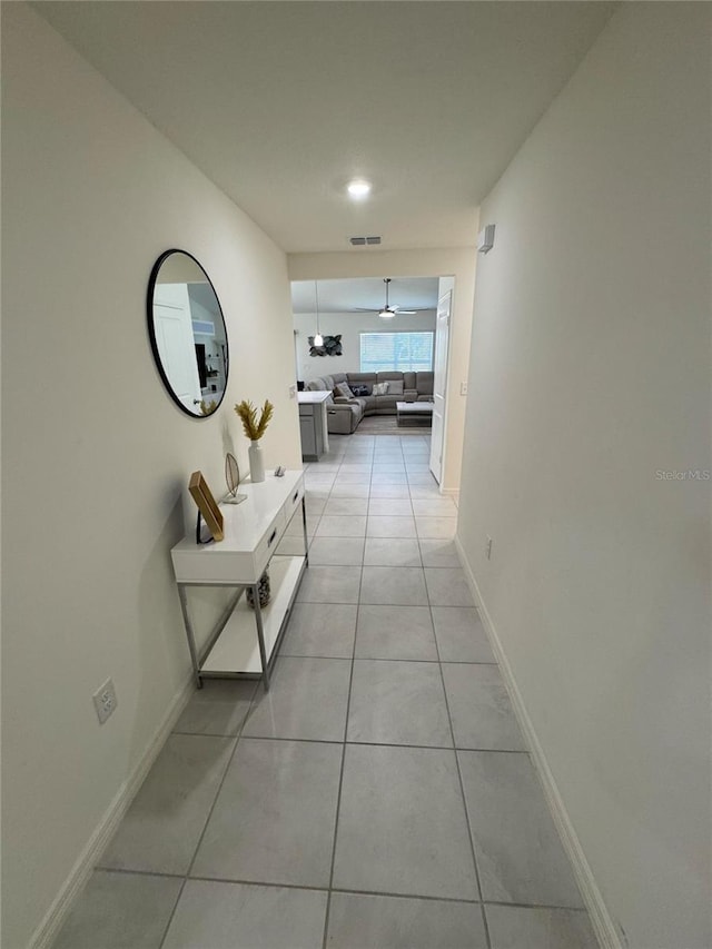 hallway featuring light tile patterned floors, visible vents, and baseboards