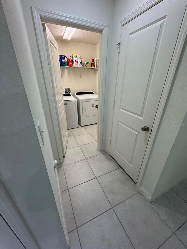 washroom with laundry area, baseboards, light tile patterned flooring, and independent washer and dryer